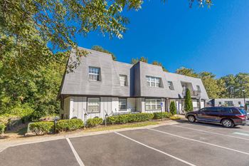a white building with a car parked in a parking lot at Pines at Lawrenceville Apartments in Decatur, GA 